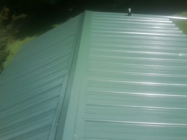 New green metal panels meeting at the ridge of a roof — Flat Roof Repair work by our crew in Reading