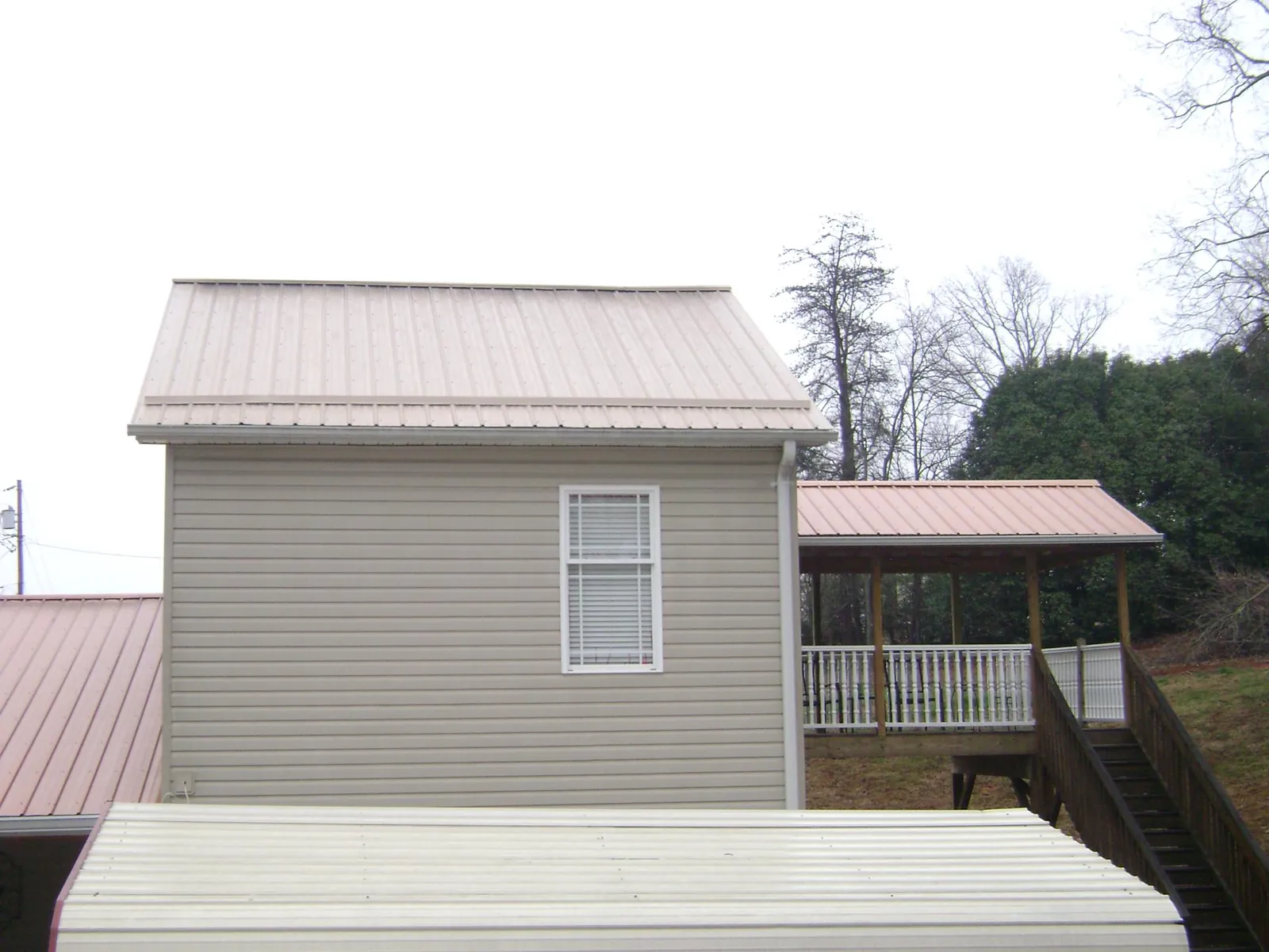 Tan metal roofs on a two story addition and attached porch, from a Roof Replacement job in Reading